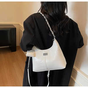 White patent leather crescent bag detail with silver logo and mini pouch accessory