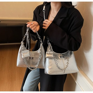 Detail of silver metallic patent leather bag with chain and mini pouch on model
