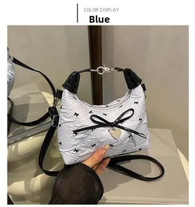 Detail of light blue bubble textured handbag with black bow embroidery and heart pendant