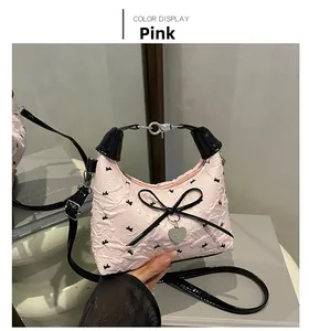 Detail of pink ballet-style handbag with black bow, heart charm and butterfly prints