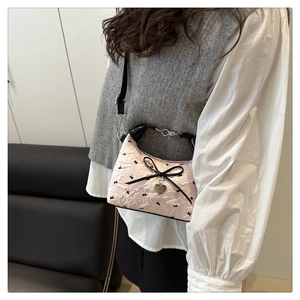 Detail of pink floral fabric crossbody bag with black bunny embroidery and bow detail