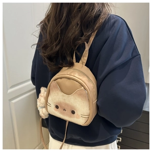 Détail d'un mini sac à dos chat avec oreilles en peluche et pendentif pompon blanc