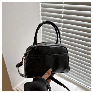 Détail d'un sac Boston noir brillant avec deux poignées et bandoulière réglable