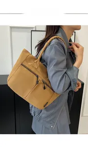 Detail of ginger yellow nylon tote bag featuring multi-pocket design and fashion label