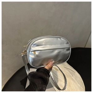 Close-up of metallic silver crossbody bag with glossy texture and golden zipper detail
