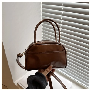 Détail d'un sac polochon rétro marron brillant avec doubles poignées et bandoulière
