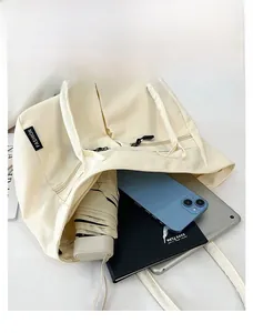 Detail view of spacious cream tote bag holding a tablet, phone, umbrella and notebook