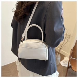 Détail d'un sac à main blanc semi-circulaire en cuir PU avec des crochets dorés sur mannequin