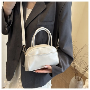Close-up of white leather handbag with gold hardware and detachable shoulder strap detail