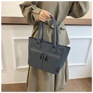 Close-up of dark grey nylon tote bag with dual decorative front zippers and fashion label
