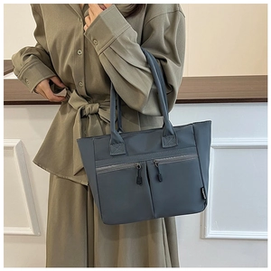 Detailed view of grey-blue canvas tote bag with side fashion label on an olive dress