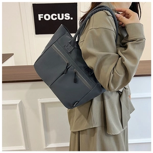 Detail view of a dark grey nylon tote bag with functional zipper pockets and fashion label