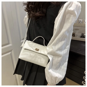 Detailed view of white woven crossbody bag with golden metal twist lock and top handle