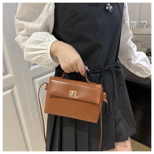 Detail of vintage brown handbag featuring woven texture and gold metal turn-lock buckle