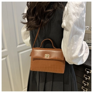 Detail of a brown vintage leather handbag featuring geometric embossing and gold twist lock