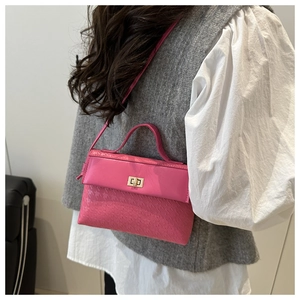 Detail of rose red satchel with houndstooth texture and stylish metal flip lock closure