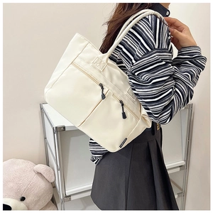 Detail of off-white nylon tote bag showing zippered pockets and fashion side label