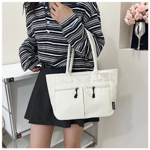 White nylon tote bag with dual front zipper pockets shown on model for daily lifestyle