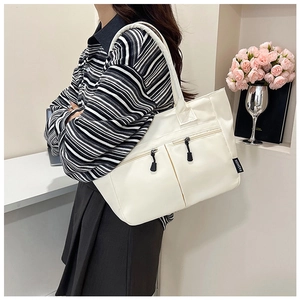 Detail of white nylon tote bag featuring external zipper pockets and black fashion label