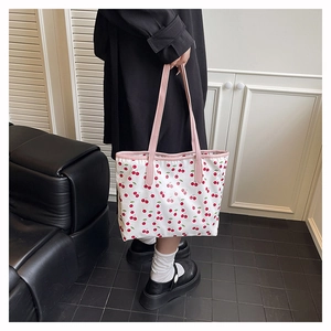 Detail of large tote bag with red cherry print and pink handles for daily use