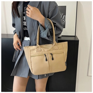 Close-up of beige nylon tote bag featuring front dual zipper pockets and fashion tag