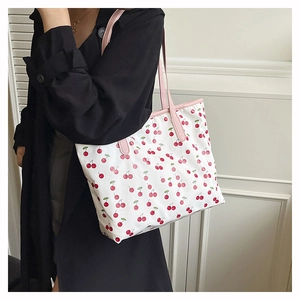 Lifestyle shot of white tote bag with red cherry prints and pink handles on model