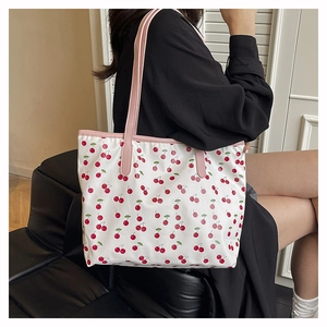 Detail of cherry print tote bag with pink leather handles and spacious interior