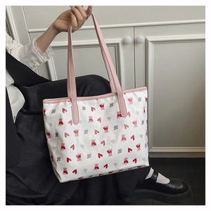Detail of white tote bag featuring pink bear patterns and durable faux leather handles