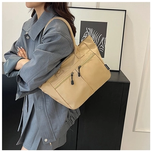 Detail of khaki nylon tote bag with zipper pocket and fashion tag on model shoulder