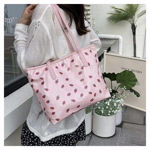 Detail of pink tote bag featuring cute red strawberry prints and wide shoulder straps