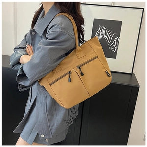Detail of ginger yellow canvas tote bag featuring three front zipper pockets and label