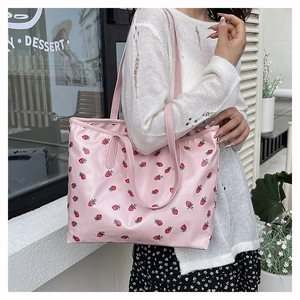 Detailed shot of pink tote bag with strawberry prints and dual handle straps
