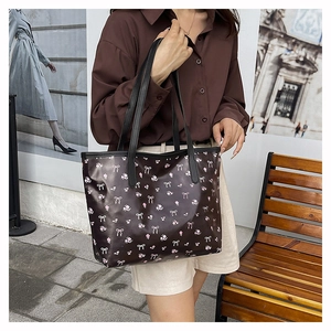 Detail of dark brown tote bag with pink floral and white bow patterns on shoulder