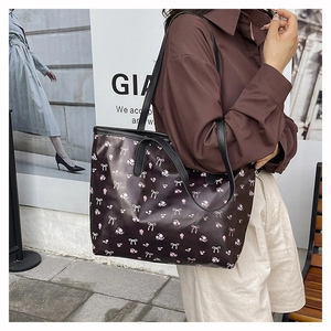 Outdoor street style view of a brown tote bag with pink bow floral prints on shoulder