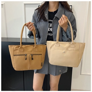 Detail view of khaki and beige nylon tote bags featuring multi-pocket design and wide handles