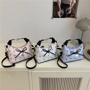 Floral fabric dumpling bag with bow and heart charm, shown in pink, white, and blue
