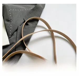 Detail of oat beige handbag with fine granular texture and gold V-shaped metal logo buckle
