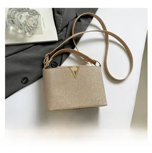 Detail of champagne gold woven crossbody bag with metal V logo and size reference phone