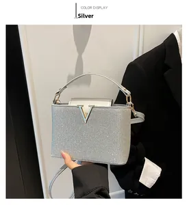 Detail of silver sequin handbag featuring a metallic V-shaped clasp and sleek handle