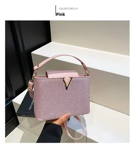 Detailed close-up of pink glitter handbag with gold V-buckle and sturdy top handle