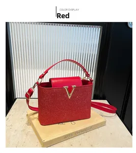 Macro detail of red sequin handbag with gold V-shaped metal buckle and premium texture