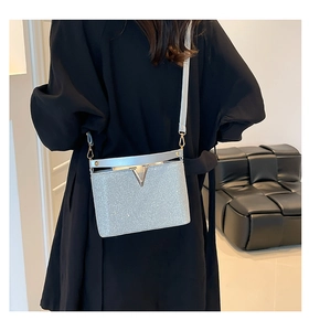 Détail du sac bandoulière carré à paillettes argentées avec fermoir en V sur un mannequin