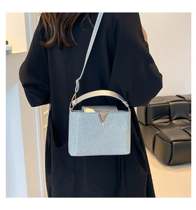 Close-up of a silver glitter handbag with a metallic V-logo clasp and chain shoulder strap