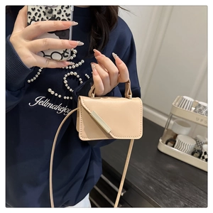 Detail of a beige mini crossbody bag with a sleek gold metal buckle and smooth leather