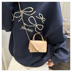 Close-up of the beige mini leather handbag with stylish gold metal trim and top handle