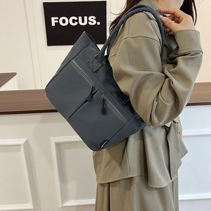 Minimalist navy nylon tote bag featuring front zipper pockets and sleek urban style