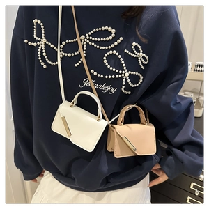 Detail of trendy crossbody bags in white and beige with metallic diagonal bars