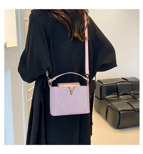 Close-up of pink sequin handbag with gold V-logo and fine glitter texture on a dress