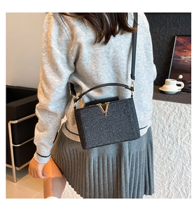 Detail der eleganten schwarzen Glitzer-Box-Tasche mit goldener V-Schnalle und Schultergurt