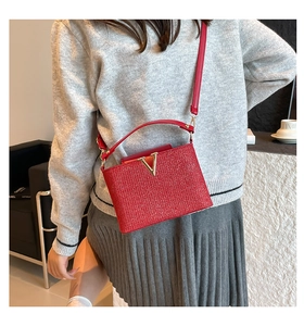 Close-up of red sequin handbag with gold V-shaped buckle and long leather strap